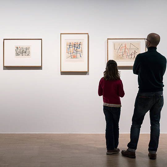 Deux visiteurs devant des toiles.