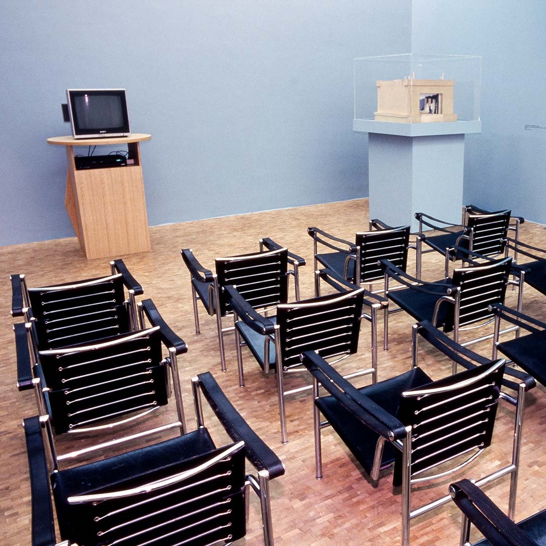 Salle de projection avec chaises tournées vers une petite télé.