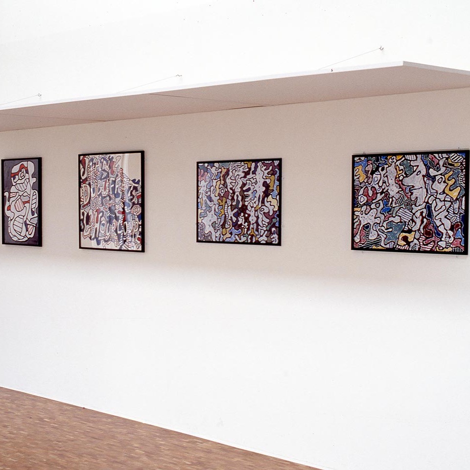 Salle d'exposition avec quatre tableaux au mur.