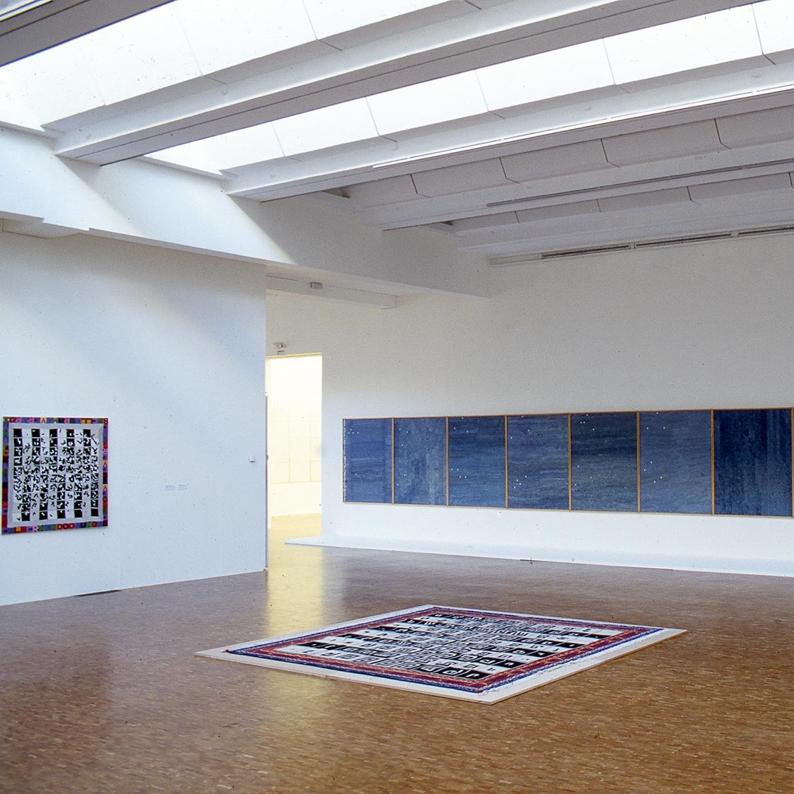 Salle d'exposition du musée avec tableaux et installation au sol.