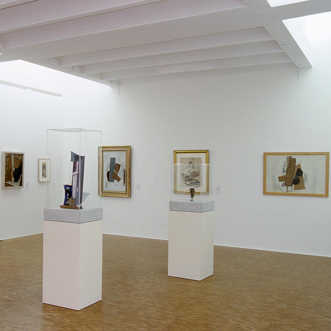 Toiles cubistes au murs et vitrines au centre de la salle.