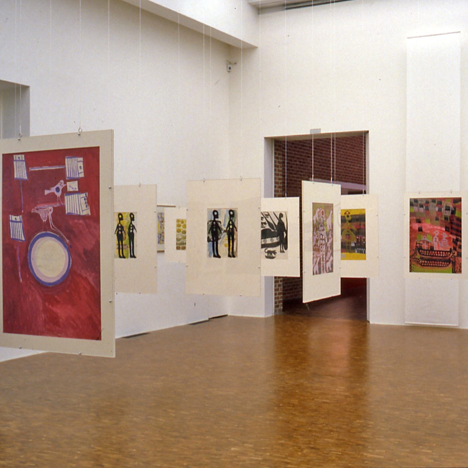 Salle d'exposition avec œuvres graphiques suspendues.