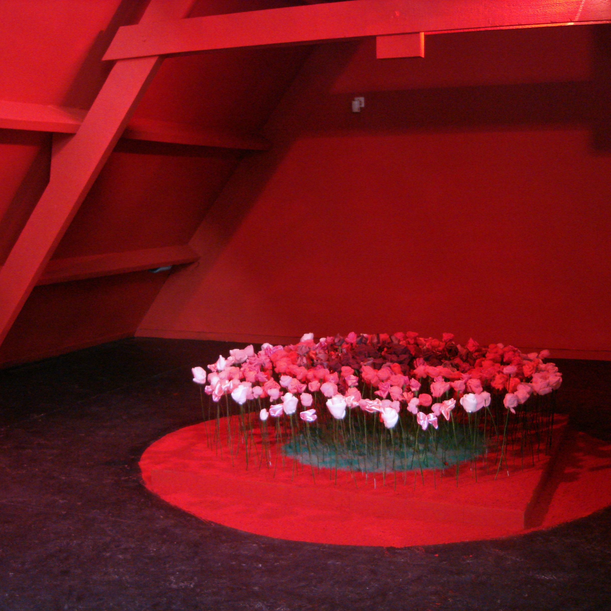Salle d'exposition rouge avec un cercle de fleurs au centre.
