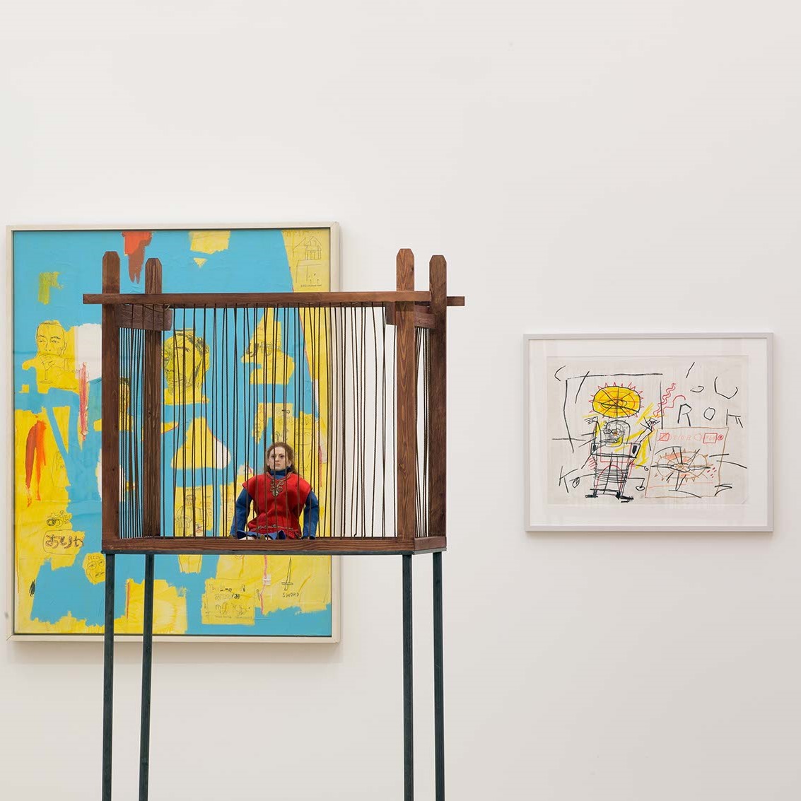 Salle d'exposition avec toiles au mur et installation.