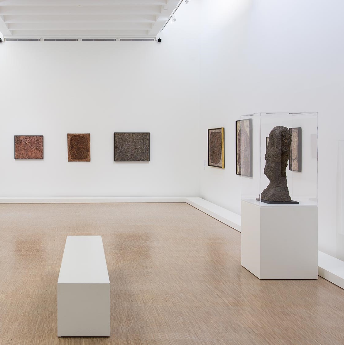 Salle d'exposition avec toiles et vitrine.