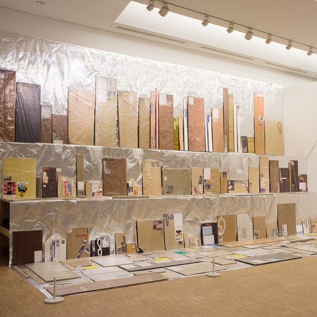 Salle d'exposition avec œuvres sur plusieurs niveaux au mur.