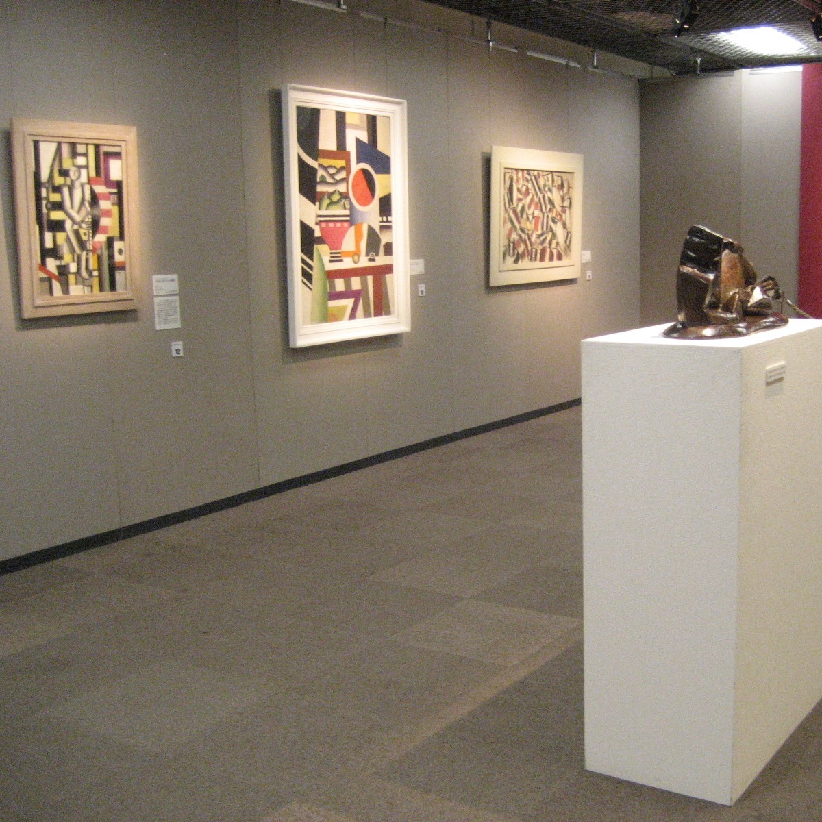 Salle d'exposition ayant une sculpture et trois tableaux.