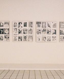 Salle d'exposition du musée avec tableaux en noirs et blancs aux murs.