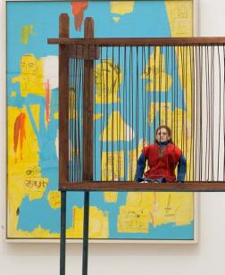 Salle d'exposition avec toiles au mur et installation.