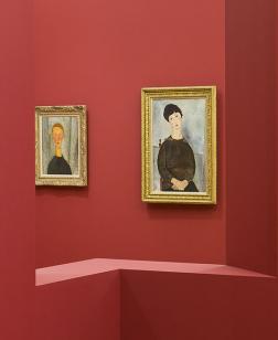 Salle d'exposition rouge avec deux toiles de Modigliani.