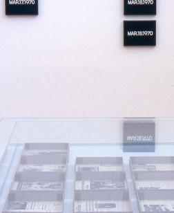 Salle d'exposition avec vitrine et œuvres au mur.