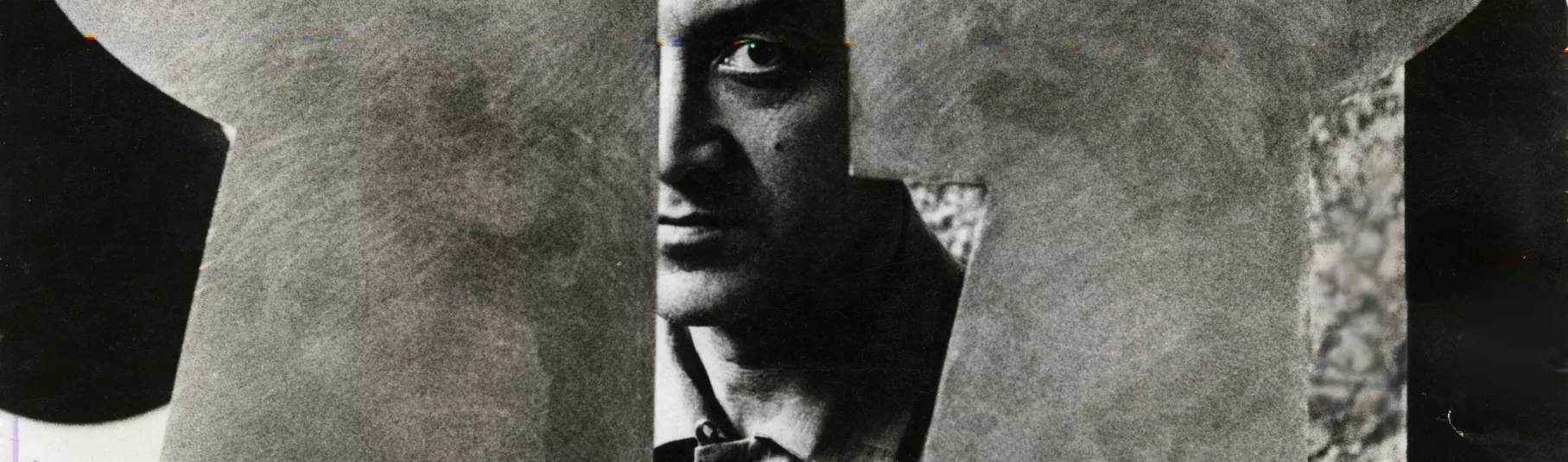 Portrait de Isamu Noguchi en noir et blanc à travers une de ses sculpture.