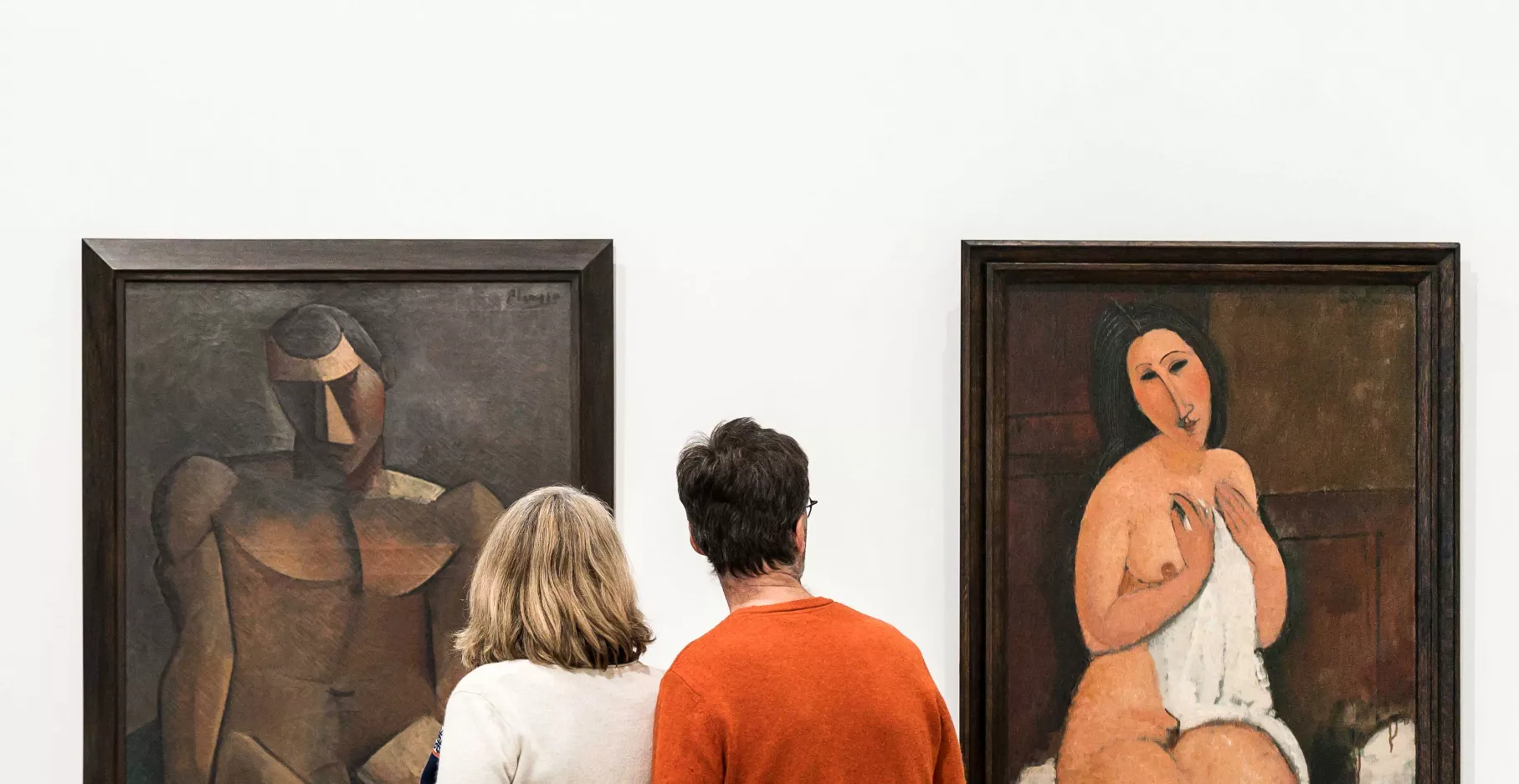 Deux visiteurs devant des toiles.