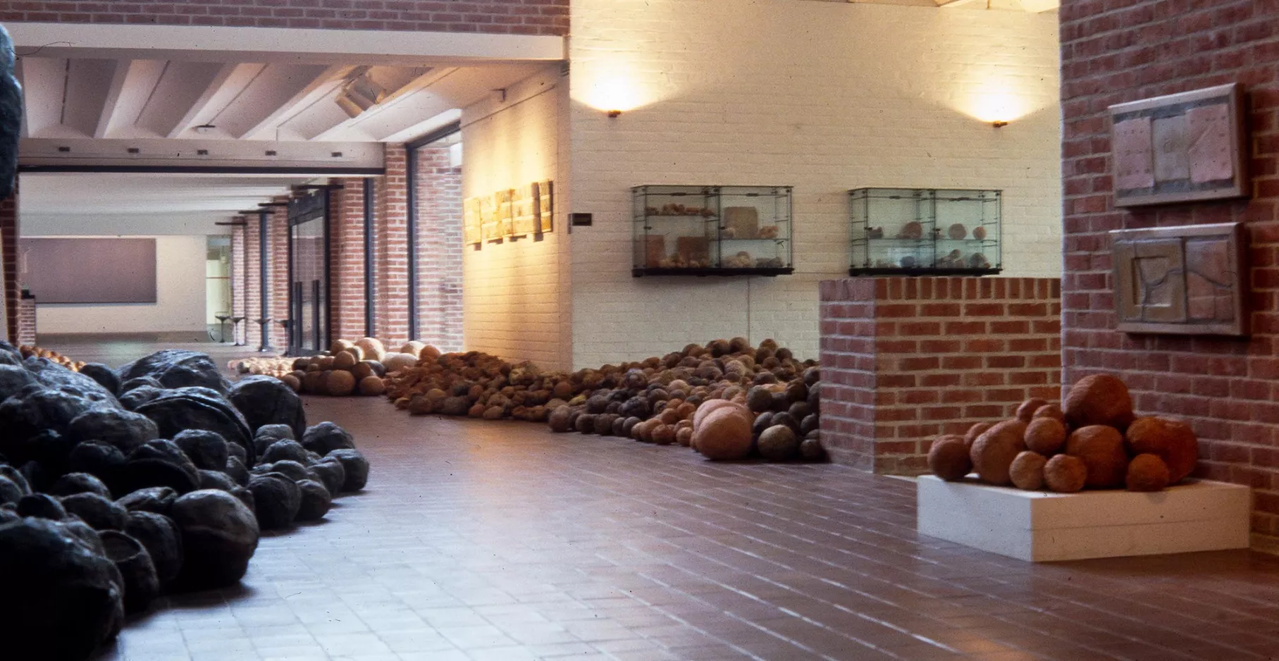 Haul d'entrée du musée envahit par une œuvre, de multiples boules s'acculent contre les parois.