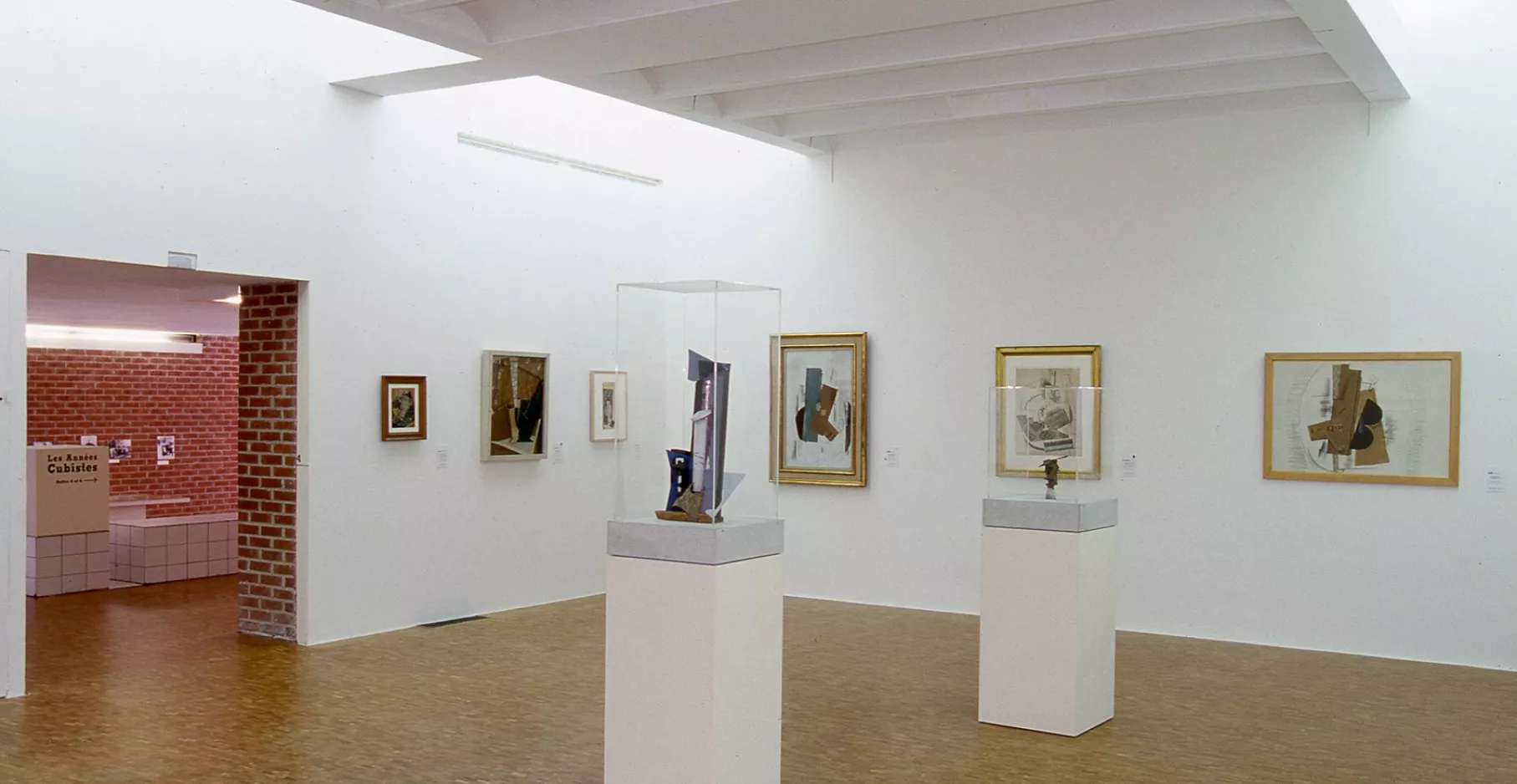 Toiles cubistes au murs et vitrines au centre de la salle.