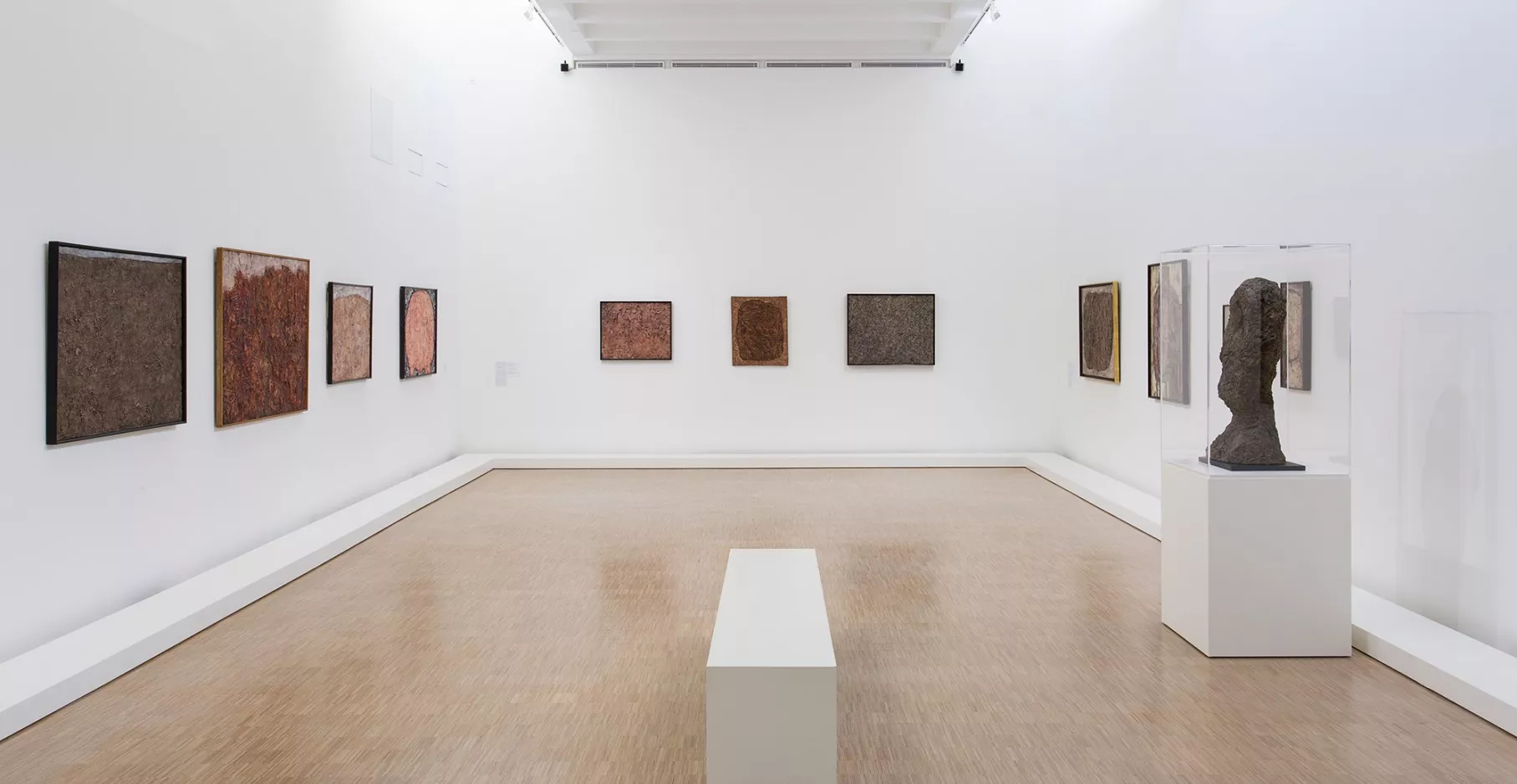 Salle d'exposition avec toiles et vitrine.