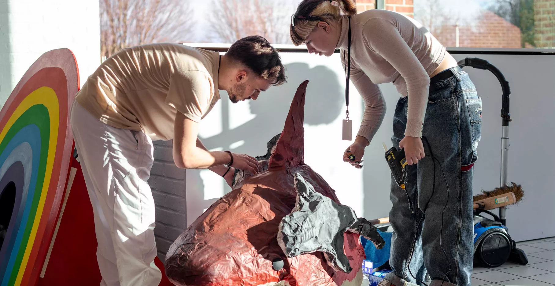 Deux personnes penchées sur des œuvres lors de l'accrochage de l'exposition entre deux mondes.