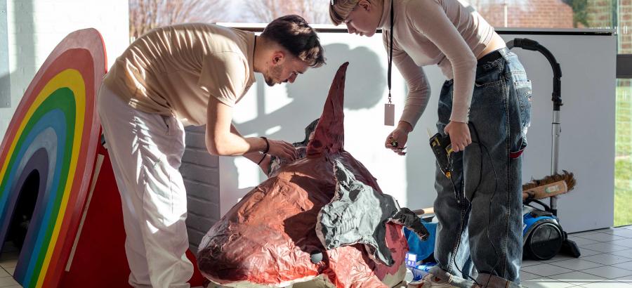Deux personnes penchées sur des œuvres lors de l'accrochage de l'exposition entre deux mondes.